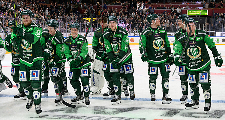 Bilden är tagen i en arena för ishockey. Spelarna står på isen och är glada.