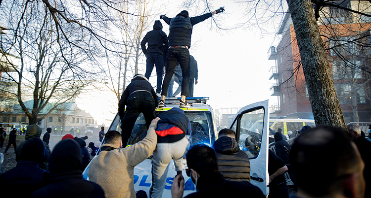 Människor står på polisernas bilar.