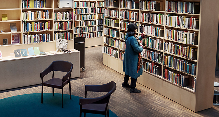 En kvinna går runt och tittar i hyllorna på ett bibliotek.
