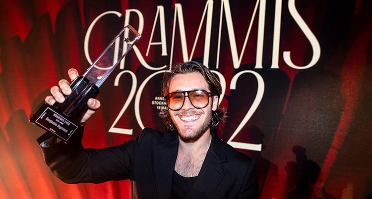 Benjamin Ingrosso håller upp priset och ler mot kameran.