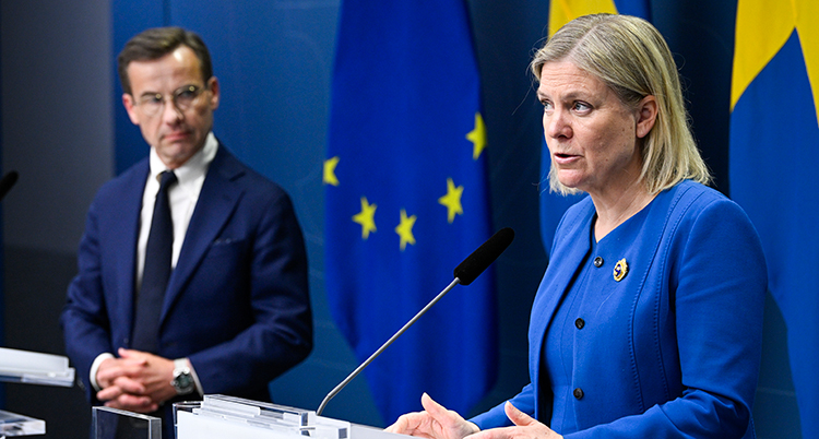 Magdalena Andersson pratar på presskonferensen. Ulf Kristersson ser på.