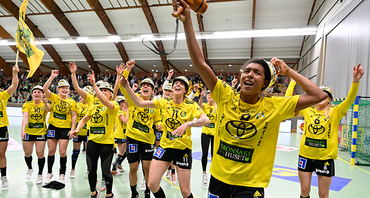 De har gula tröjor, står på en plan och jublar med händerna mot luften