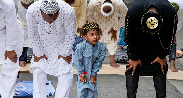 En muslimsk pojke ber tillsammans med tre män.