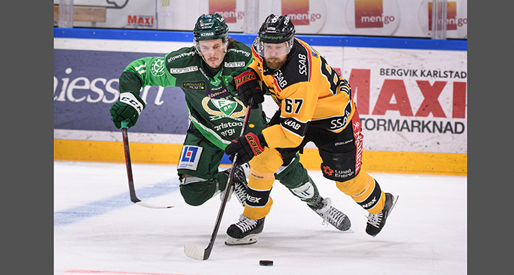 De kämpar om pucken på isen. De har hockeyutrustning och klubbor.
