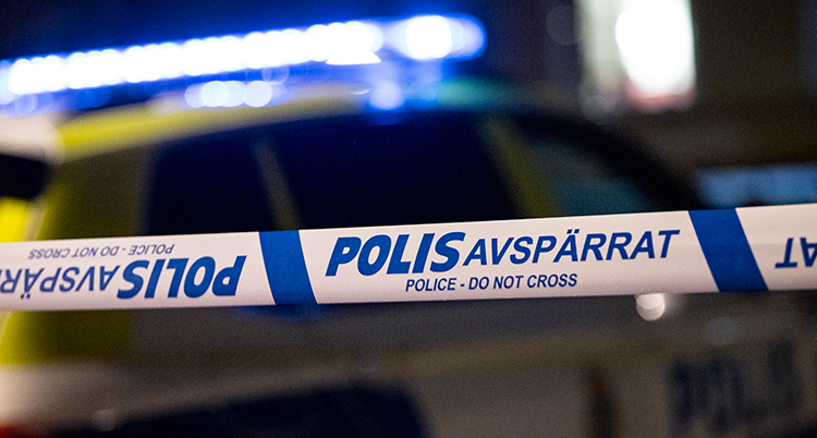 Ett band som visar att poliserna har spärrat av en plats. I bakgrundens syns en polisbil.