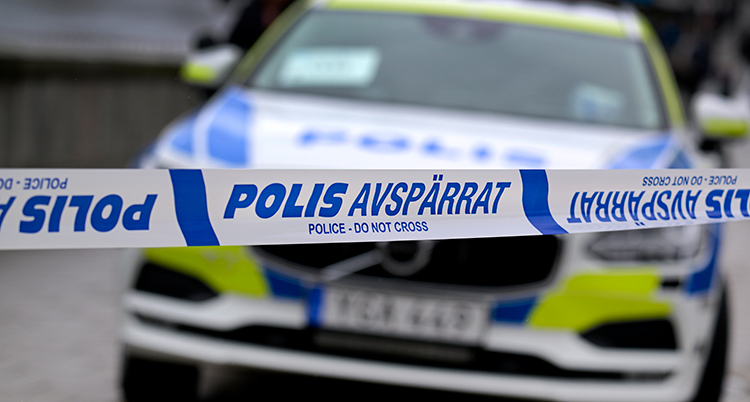 en polisbil bakom en avspärrnig med polisband.