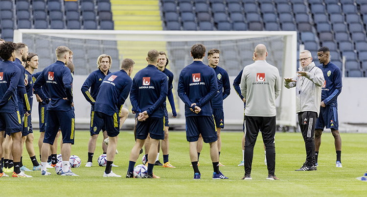 En tränare pratar med sina spelare på en fotbollsplan.