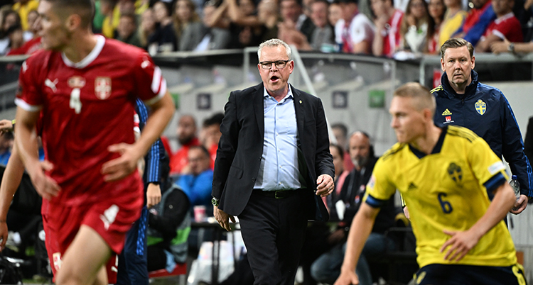 Fotbollsledare i kostym och några fotbollsspelare i förgrunden.