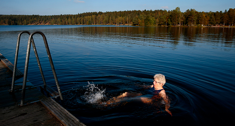Hon badar i en sjö, hon sparkar med benen i vattnet. Hon är i vattnet nedanför en brygga.