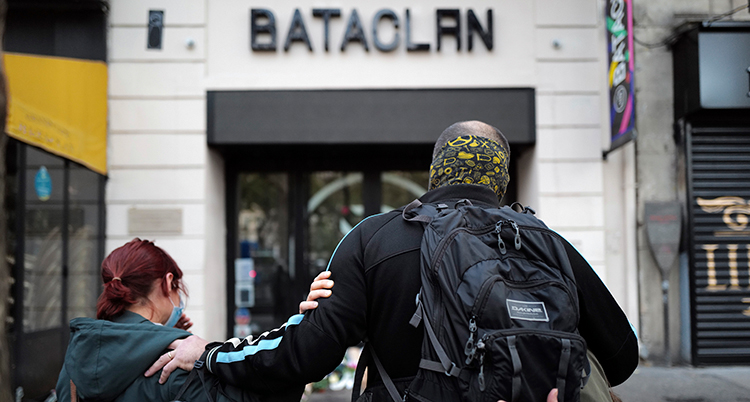 Ryggen på en kvinna och en man syns mot kameran. De står och tittar mot en lokal. På en skylt på lokalen står det Bataclan.