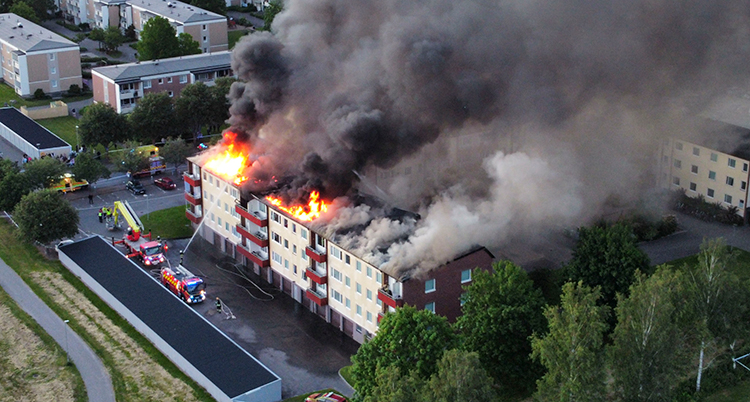 En flygbild över huset. Den kommer rök och eld fråmn taket.