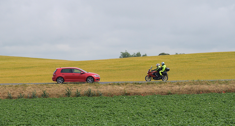 En bil och en motorcykel framför ett rapsfält.