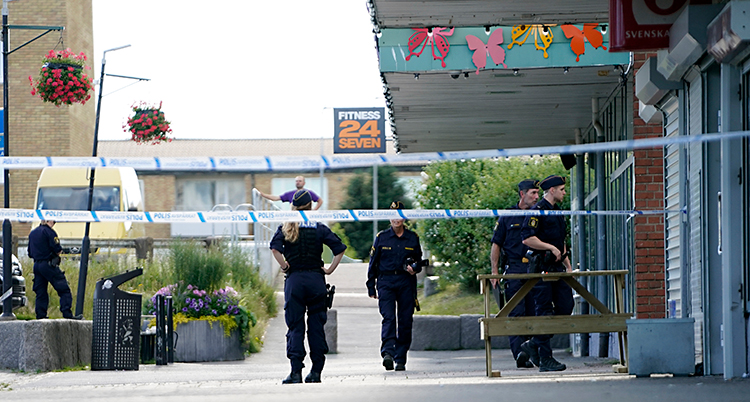 Fem poliser står utanför en affär i ett centrum.