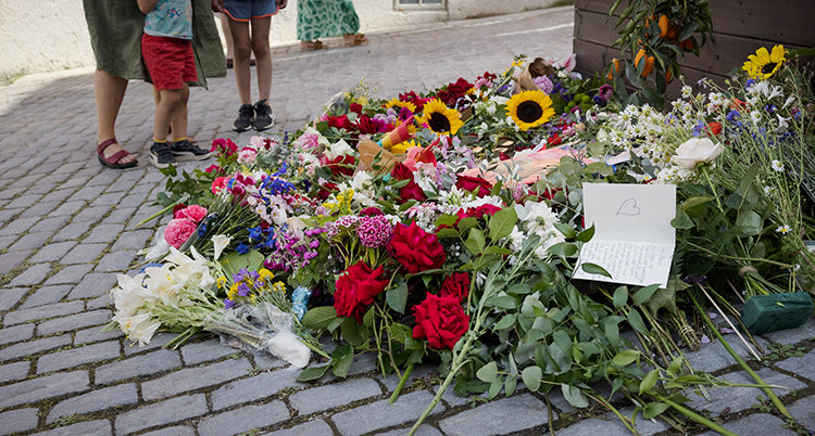 Massor av blommor på en kullerstensgata.