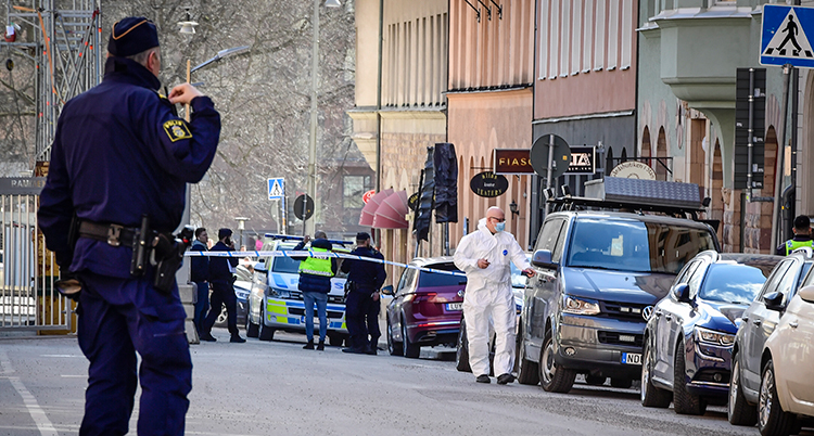 En polis tittar ned längs en gatan med avspärrningar.