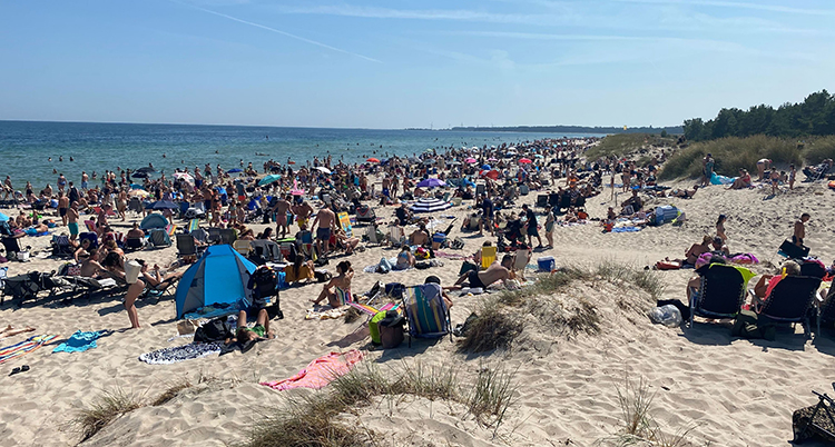 Människor sitter på en sandstrand.