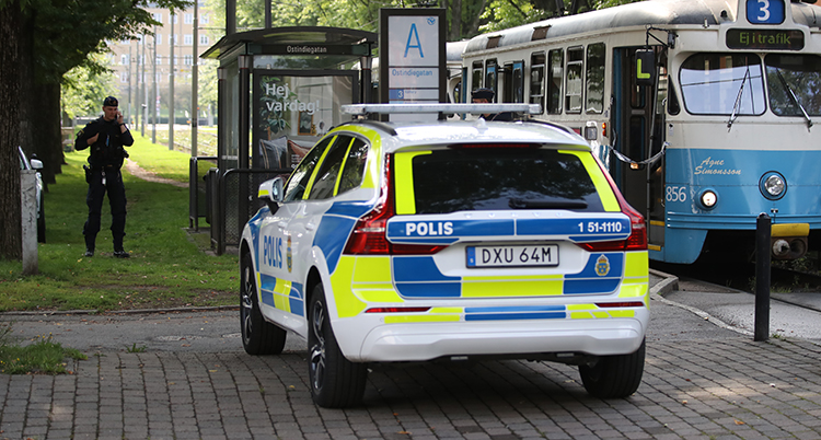 En polisbil står på hållplatsen. Där står också en spårvagn.