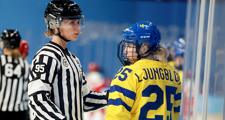 En domare pratar med en ishockeyspelare på isen.