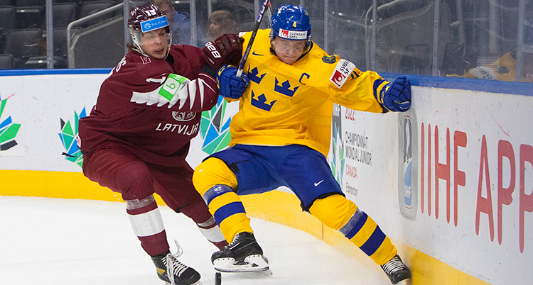 Två hockeyspelare tampas om pucken.