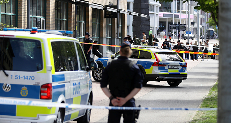 En gata avspärrad av poliser. Människor står vid avspärrningarna.