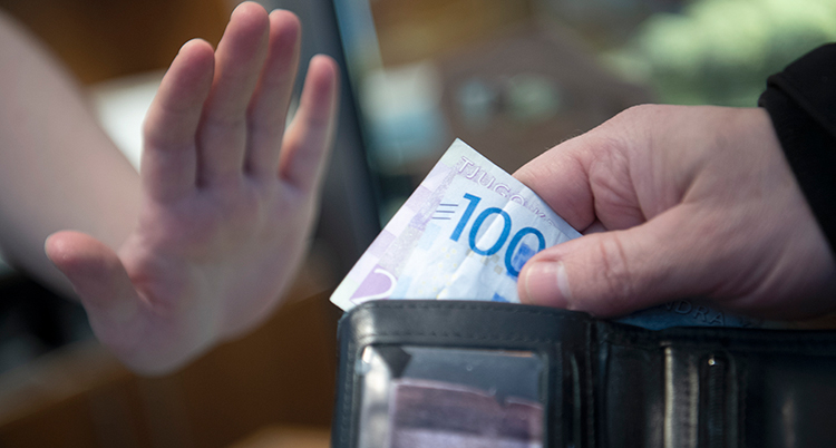 En han tar upp en sedel och en annan hand signalerar nej tack.