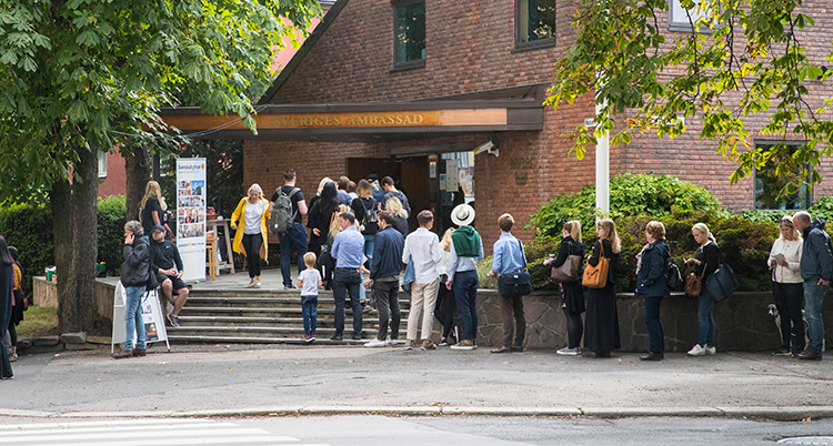 Människor i kö utanför ett hus av tegel.