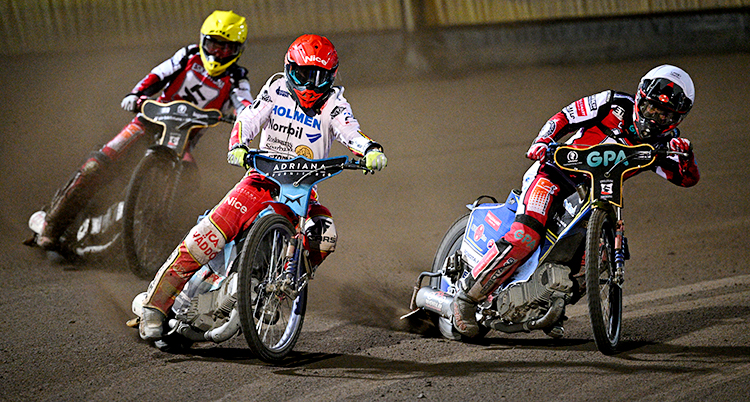 Tre förare på speedwaycyklar på en speedwaybana.