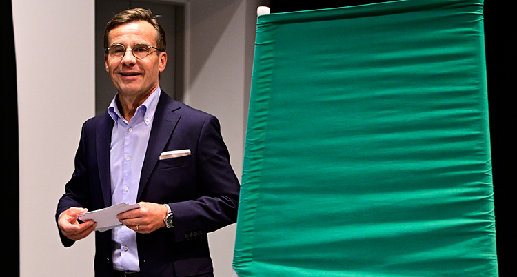 Han står bredvid ett grönt valbås