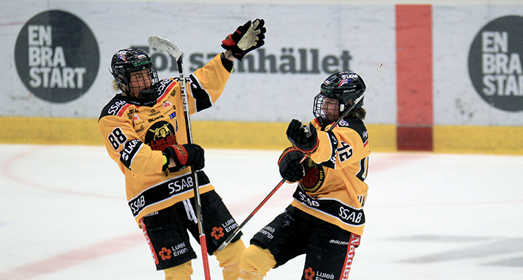 De har gula tröjor på sig och firar på isen.