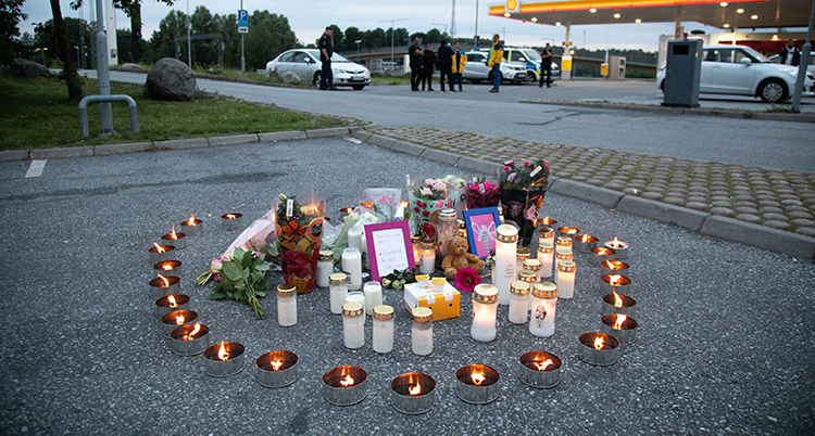 Ljusen står i en cirkel på en parkering. I mitten ligger blommorna.