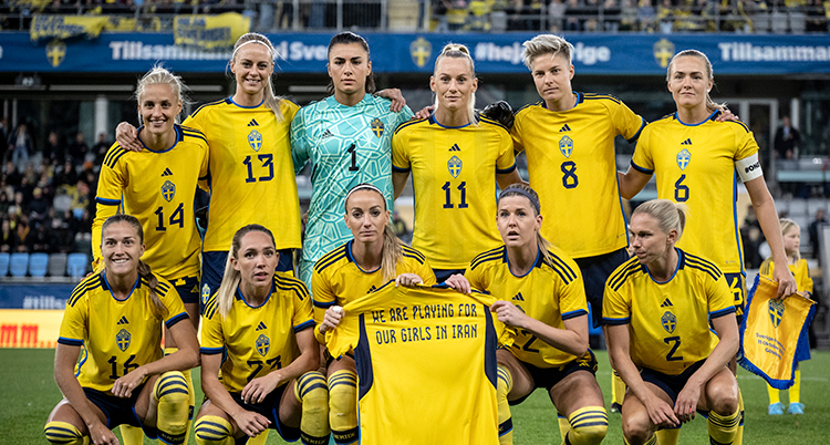 Sveriges elva spelare blir fotade. Två av dem håller upp tröjan med hälsningen.