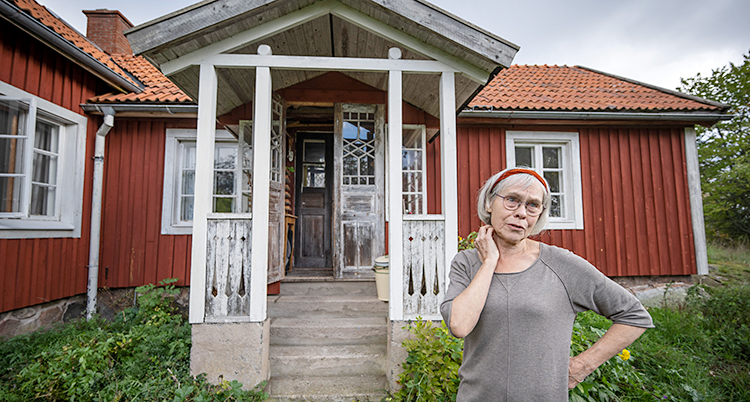 Hon står utanför ett rött hus.
