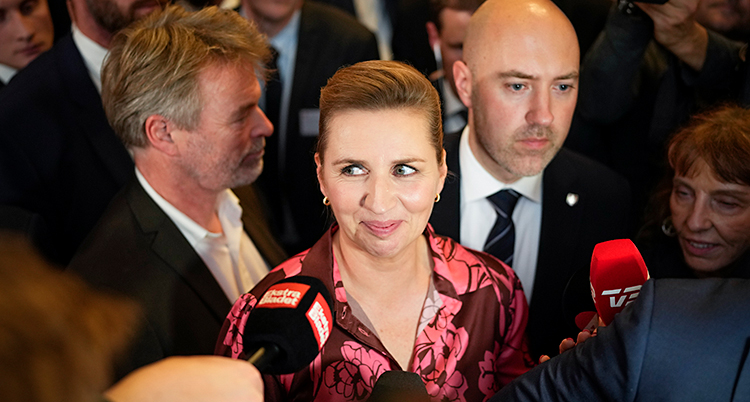 Hon ser glad ut. Flera journalister sträcker fram sina mikrofoner mot henne.