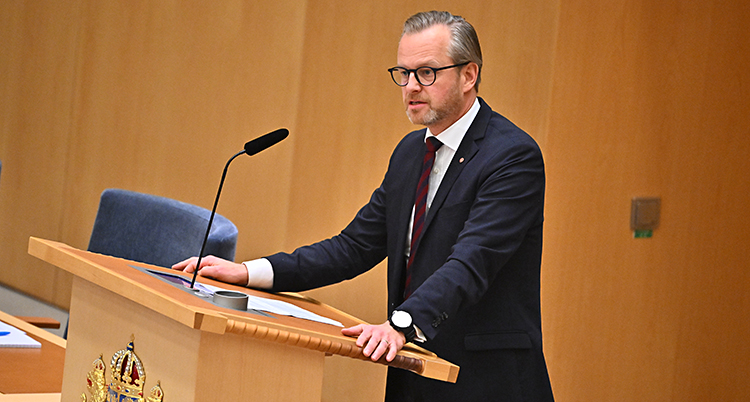 Han står och pratar i riksdagen.