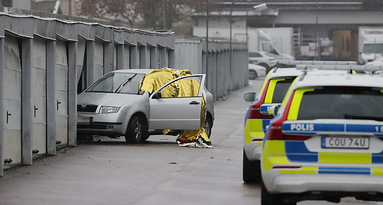 En bil har rullat in i porten till ett garage. Flera polisbilar står i närheten.