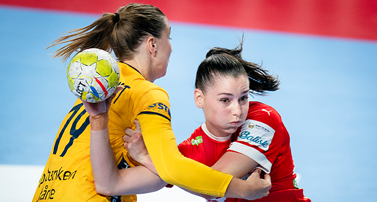Två kvinnor kämpar om bollen i en match i handboll.