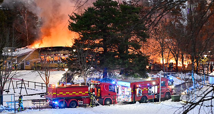 Det brinner i en gul byggnad. Flera brandbilar är där.