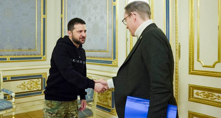 De tar varandra i hand. Zelenskyj har svart luvtröja. Billström har svart kavaj. Rummet har guldramar på väggarna.