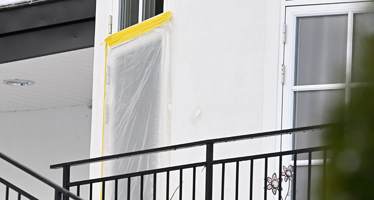 En dörr i ett vitt hus är skyddad med plast. Troligen har dörren gått sönder när poliserna tog sig in.