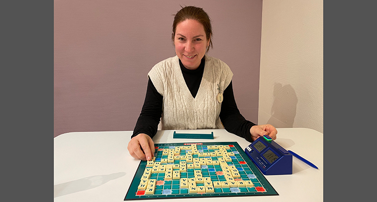 Hon sitter vid ett bord med ett brädspel framför sig