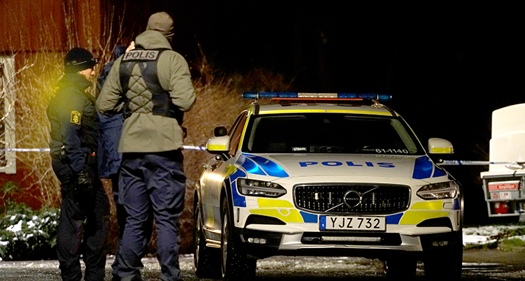 En polisbil med två män bredvid.