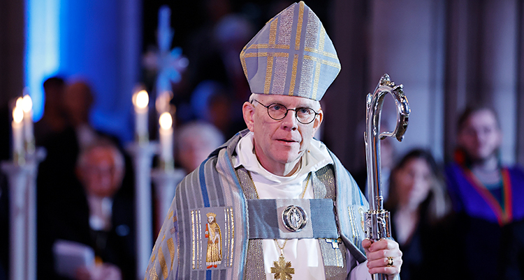 Han står i en kyrka med en hatt på huvudet.