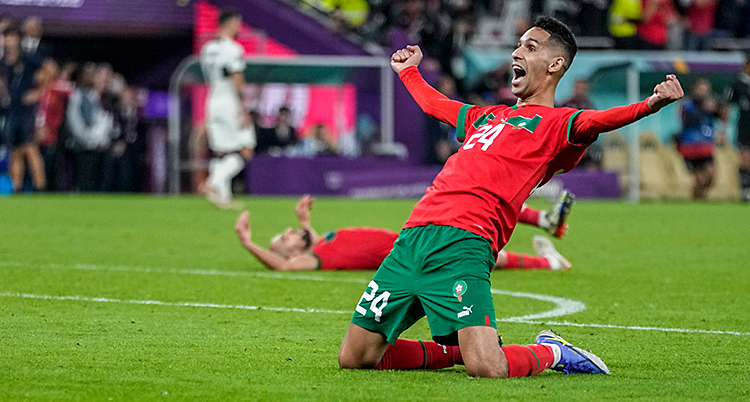 Han står på knä på en fotbollsplan och skriker ut sin glädje.