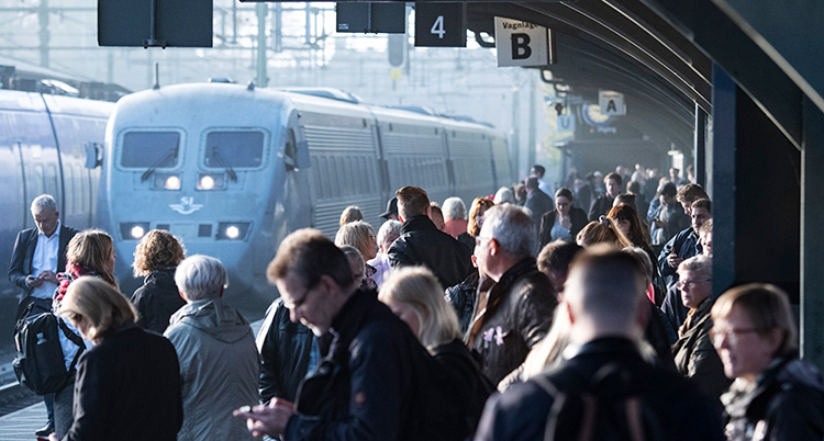 Folk står vid ens station och väntar på ett tåg.
