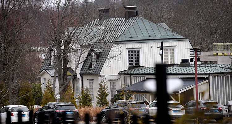 Ett vitt stort hus fotat en bit ifrån. Ett staket syns i förgrunden.