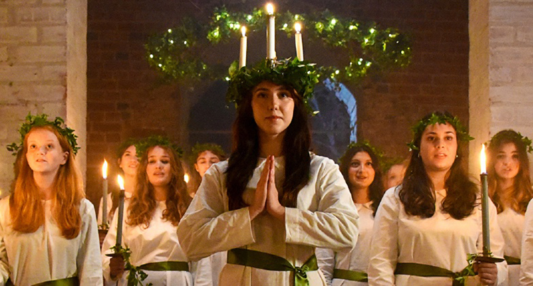Lucia med krona på huvudet och många tärnor omkring