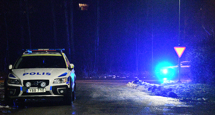 En polisbil står på en väg. Det är mörkt ute.