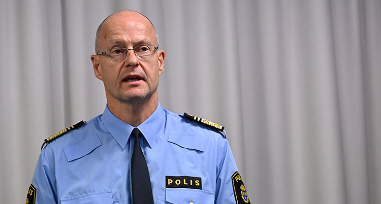 Han har uniform och pratar på en träff för journalister.