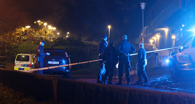 Poliser står utomhus i mörker.
