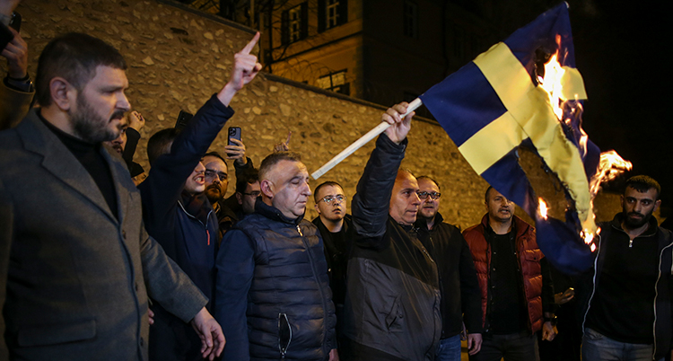 En grupp män håller upp en brinnande flagga.